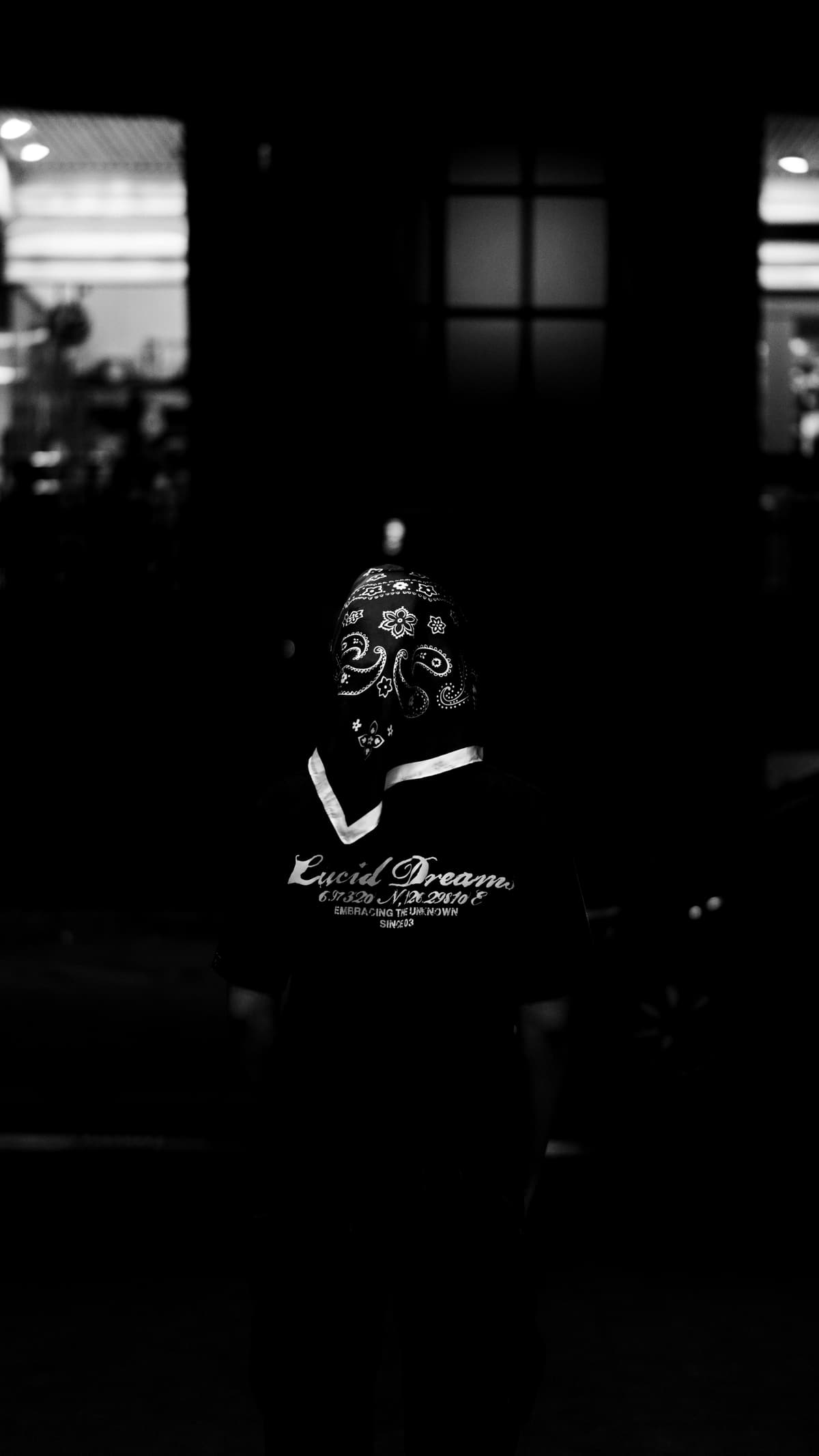 A model in a patterned bandana, from behind, showing the shirt's Lucid Dreams back print